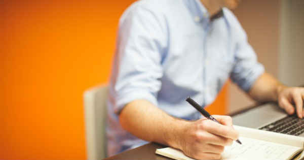 man writing a script while sitting at a his desk