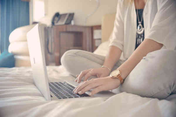 woman working in bed on apple laptop